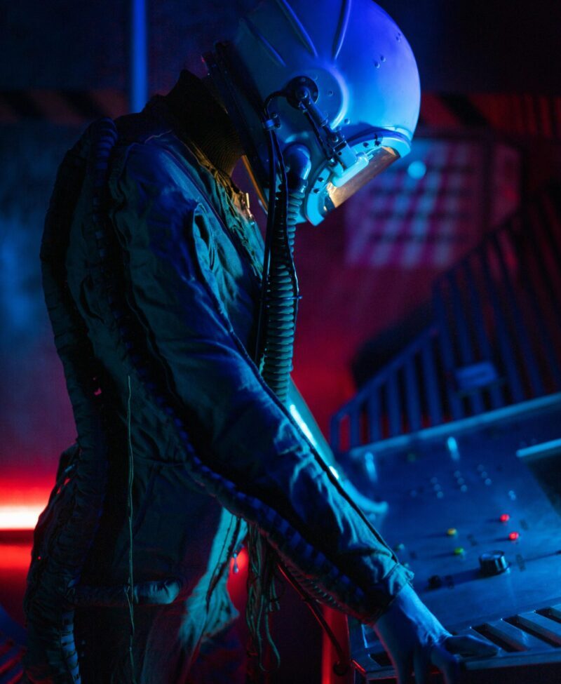 Side view of an astronaut in a futuristic, illuminated space setting, operating controls.